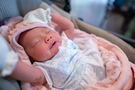 Newborn Baby Girl Sleeping Peacefully in Bassinet Wearing Pink Hooded Blanket