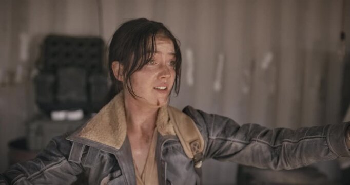 Frightened, filthy woman in shed holding up hands and trying to defuse tense situation