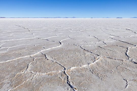 View of the vast Uyuni Salt Flat showing the unique hexagonal salt crust patterns under a clear blue sky in Potosi Department, Bolivia.
