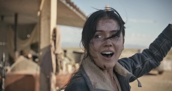 Dirty, angry woman in sci-fi area holding up ball then turning and smiling at something approaching