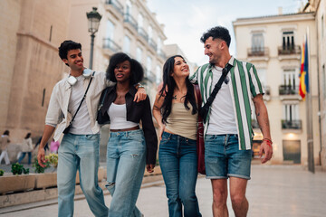 Obraz premium Diverse young friends enjoying city walk, smiling and talking together, sharing joyful moments