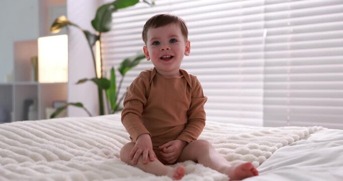 Cute little baby boy on bed at home