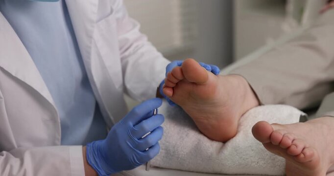 Woman undergoing toenail treatment during visit to podiatrist in clinic, closeup. Camera moving up