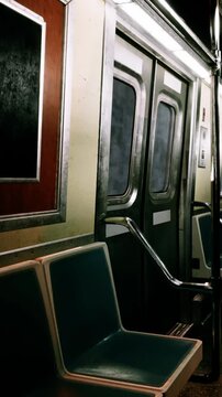Inside a subway car, there are empty blue seats beside closed doors. The train is quiet and has bright lights overhead. The time appears to be morning.