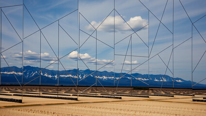 Fototapeta premium Geometric Sculpture Amidst Golden Fields and Snow-Capped Mountains