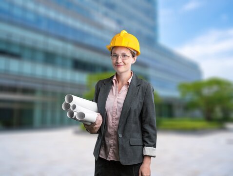 Female architect holds architectural blueprints posing outdoor