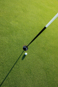Looking down at golf ball next to green hole