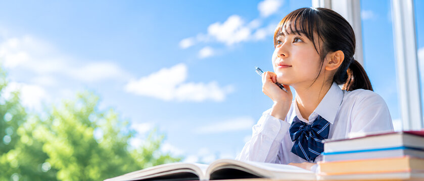 青空を見上げながら将来を考える女子高校生の学習イメージ