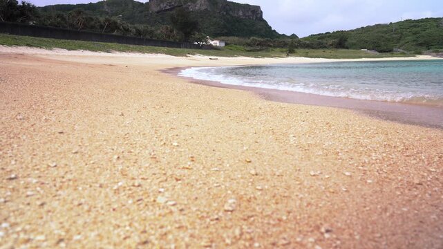 Low angle shot of gentle waves lapping on the coral sand beach of Nanta Beach in Yonaguni Island, Okinawa, Japan