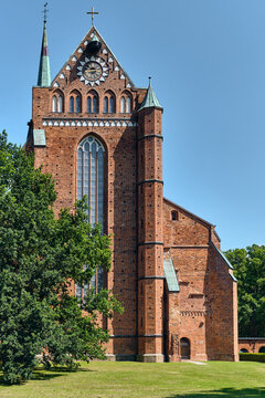 Bad Doberan, Germany - 19 July 2025: View of the Doberaner Munster showing its red brick Gothic architecture, large stained glass window, and decorative clock gable under a blue sky.