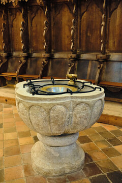 Bad Doberan, Germany - 19 July 2025: View of the historic stone baptismal font and carved wooden choir stalls inside the Doberaner Munster.