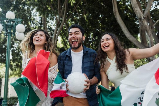 group of mexican soccer fans holding a soccer ball and national flag supporting to their sport team outdoors in Mexico city in Latin America