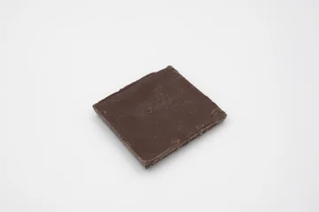 Square piece of dark chocolate on white surface © jr-art