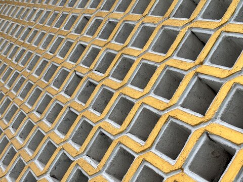 Abstract geometric pattern of concrete breeze blocks painted in white and gold. Diagonal perspective of a decorative ventilation wall texture.