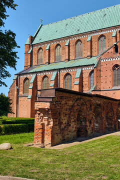 Bad Doberan, Germany - 19 July 2025: View of the Doberaner Munster featuring red brick Gothic architecture, a green copper roof, and ancient ruins under a clear blue sky.