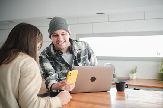 Remote work team, couple looking at a mobile phone to plan their work on a laptop. Concept of remote work and teamwork.