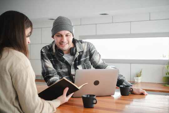 Remote work team, couple looking at a mobile phone to plan their work on a laptop. Concept of remote work and teamwork.