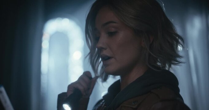 Closeup of woman staring at something with flashlight and putting phone reviver to ear
