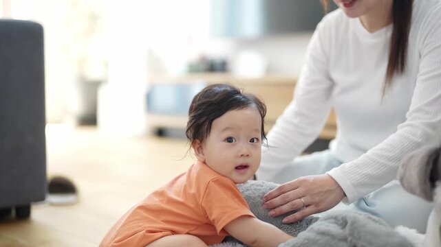 Soft light fills a cozy home. Child smiles, curious and joyful. Mother kneels, warm and loving. They share a quiet, tender moment. Perfect for family or parenting themes. No animals or plants visible