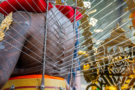 View of a devotee with metal skewers piercing his back during a religious ritual near Sri Srinivasa Perumal Temple in Singapore, Singapore.