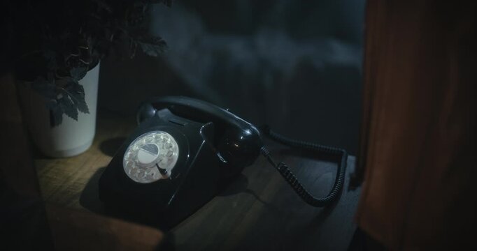 Woman pointing flashlight at rotary phone then picking up receiver in spooky house- tilt shot