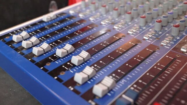 Audio mixing console with faders and control knobs
