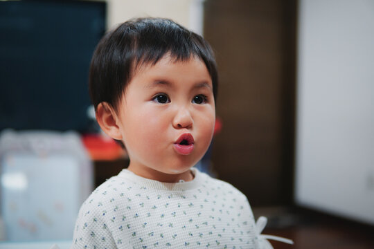 Portrait of a cute little Asian girl making a funny pouting expression at home