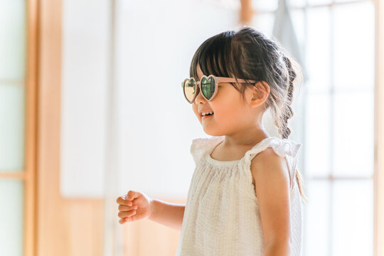 A girl wearing sunglasses plays pretend as a model in a fashion show.