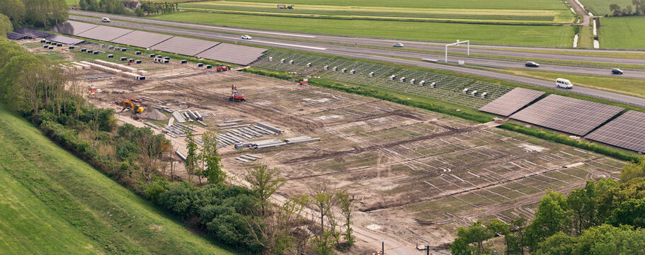 Den Oever, Netherlands - 21 May 2026: Aerial view of solar park construction on the A7 highway embankment near Stevin Sluices as part of the Afsluitdijk renewal project.