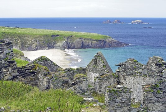 Ruins on a rocky coast with green grass and blue sea, Blasket Islands, Dunmore Head, Ireland