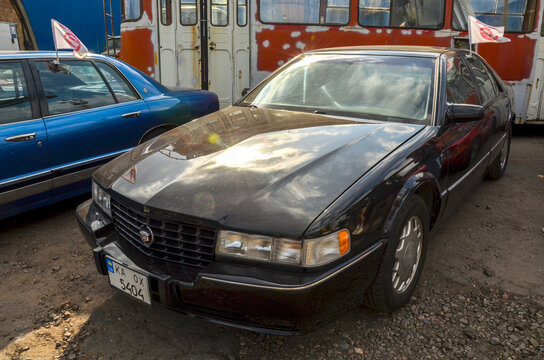 Black Cadillac Seville STS (fourth generation) featuring a bold egg crate grille and classic American luxury styling. This 1990s sedan is displayed at a car meet