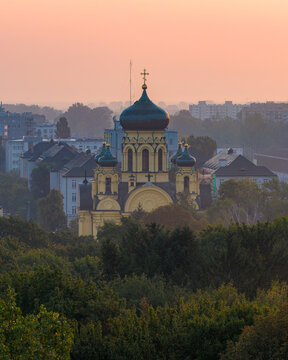 Warsaw, Poland - 05 September 2025: Aerial view of the Metropolitan Cathedral of Saint Mary Magdalene with its green domes and golden crosses rising above lush trees and city buildings.