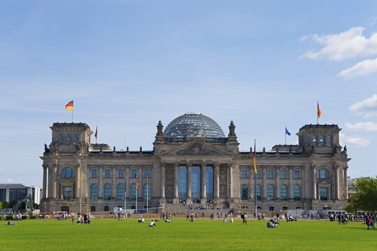 The Reichstag in Berlin with its striking glass dome and German flags on a large lawn, Reichstag building, German Bundestag, Berlin, Germany