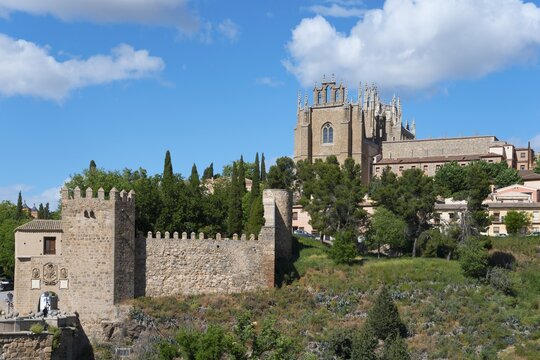 Medieval cityscape with church, city walls and trees under a blue sky with clouds, Puente de San Mart&iacute;n, St Martin's Bridge, monastery on the right, Monasterio de San Juan de los Reyes, Toledo, Castilla-La Mancha, Spain