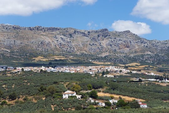A picturesque village surrounded by olive groves under a clear blue sky with mountains in the background, Villanueva de la Concepci&oacute;n, La Villa de Torcal, nature reserve, El Torcal de Antequera, Sierra del Torcal, M&aacute;laga province, Malaga, Andalusia, Spain