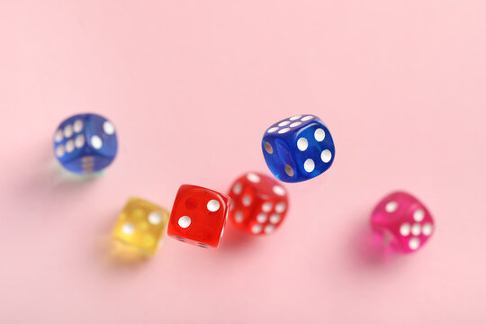 Flying colorful game dices on pink background