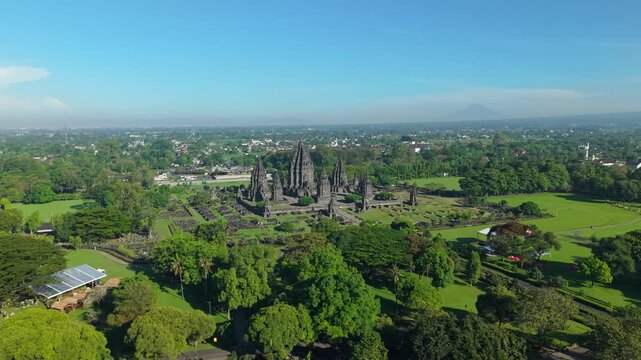 Aerial view of Prambanan Temple with its ancient stone spires surrounded by lush green gardens and trees in Kecamatan Prambanan, Daerah Istimewa Yogya, Indonesia.
