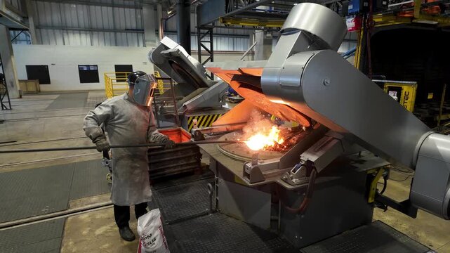 Cinematic industrial footage featuring molten metal pouring from a high-temperature furnace inside a modern manufacturing facility. Intense heat, glowing steel, sparks, heavy machinery, and industrial