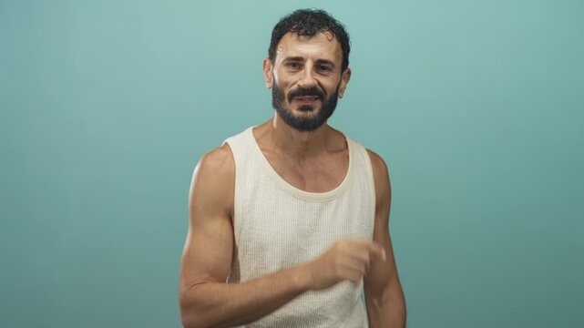 Man with beard and bare forearm, finger to lips for silence in a studio against teal backdrop; quiet secrecy.