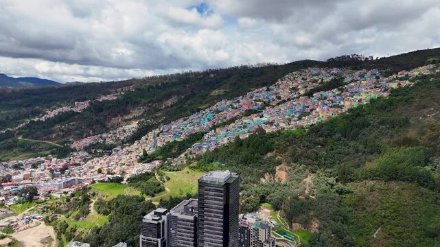 Vibrant houses painted in various colors ascending a hillside under a cloudy sky, showcasing urban transformation in Bogot&aacute;, Colombia.