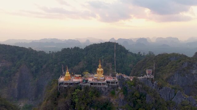 Krabi Noi, Thailand - 24 May 2026: Aerial view of the golden Buddha statue and stupa at Tiger Cave Temple viewpoint surrounded by lush mountains.
