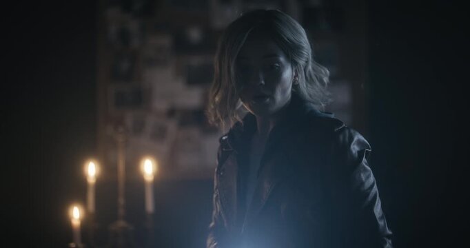 Cinematic silhouette of beautiful yet frightened woman with flashlight in spooky home 