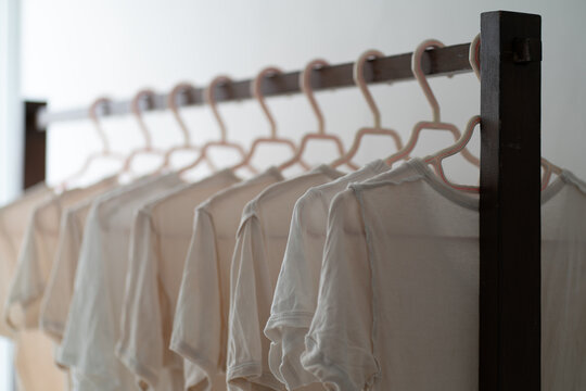 White Undershirts Hanging on Clothing Rack in Soft Natural Light