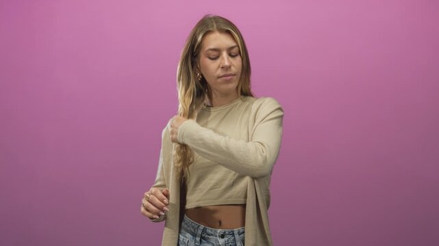 Woman young blonde runs hand through long hair showing bare midriff and crop top in studio; calm reflection.