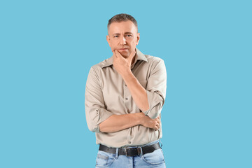 Fototapeta premium Mature man suffering from toothache on blue background