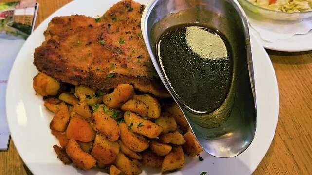 Traditional breaded pork schnitzel dinner with fried potatoes, rich brown gravy and side salad, warm restaurant food scene featuring classic German cuisine and hearty European comfort meal.