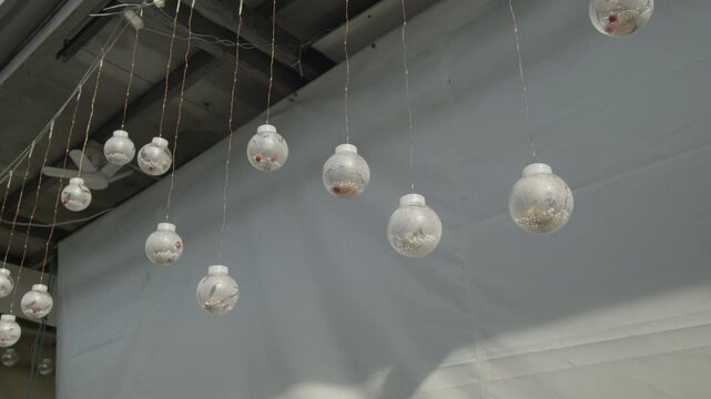 A close-up shot of several clear glass spheres filled with small white decorative items, hanging by copper wires against a neutral white background.
