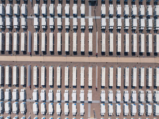 Obraz premium Aerial view of neatly arranged container trucks parked in a large logistics yard