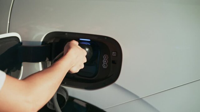 4K slow motion person charging electric car at home.	
