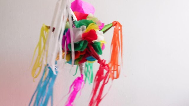 A small colorful pi&ntilde;ata swings. Illuminated by light of various colors